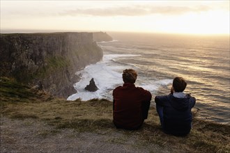 Two men sitting on The Cliffs of Moher