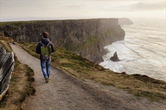 Mid adult man walking on The Cliffs of Moher