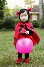 Young girl dressed up as ladybird with trick or treat bucket