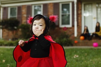Girl dressed as ladybird with hand on mouth