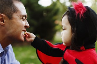 Girl dressed as ladybird feeding father
