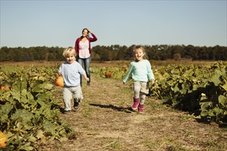 Mother with two children in pumpkin field