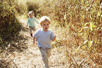 Boy and girl running in field with crops