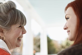 Close up of senior woman and adult daughter laughing on porch