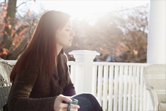 Young woman drinking coffee with eyes closed in porch