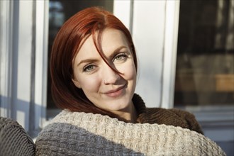 Portrait of young woman with red hair on porch