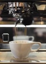 Coffee flowing from coffee machine in coffee shop