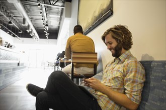 Young man sitting in coffee shop using smartphone