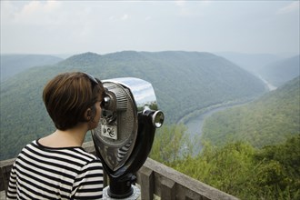 Mid adult woman looking through coin operated binoculars