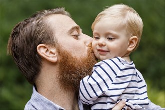 Portrait of father kissing baby girl