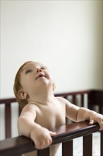 Toddler holding on to edge of cot