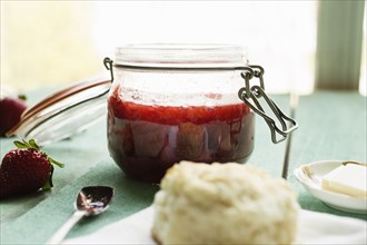 Jar of homemade strawberry preserve with biscuits