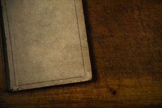 Old book with blank cover resting on old wooden desk top