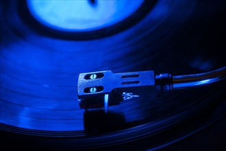 Close-up of a record player needle on record in blue light