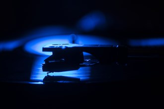 Close-up of a record player needle on record in blue light