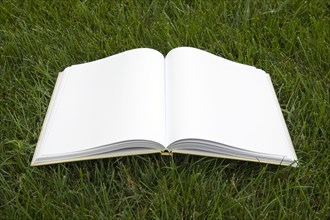 Open book with blank pages on grass