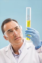 Scientist looking at yellow liquid in measuring beaker