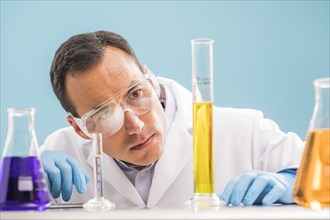 Scientist looking at yellow liquid in measuring beaker