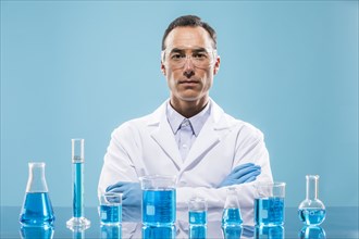 Portrait of scientist with beakers with blue liquid in foreground