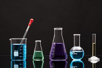 Laboratory glassware with liquids against black background
