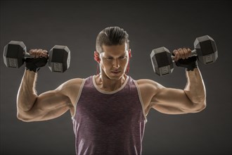Muscular man training with dumbbells