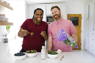 Smiling couple making salad in kitchen
