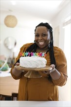 Smiling woman holding birthday cake