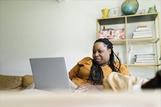 Woman sitting on sofa and working on laptop