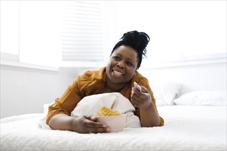 Woman eating potato chips in bed