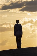 Silhouette of woman standing against sunset sky