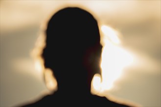 Defocused silhouette of woman's head at sunset