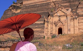 Buddhist nun in front of old Buddhist temple ruined by earthquake