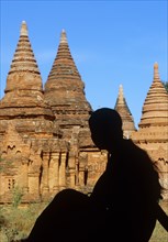 Silhouette of young woman sitting in front of Buddhist pagodas
