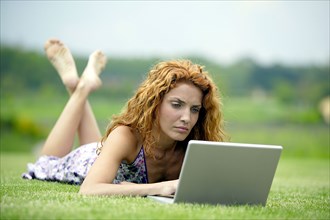 Woman with laptop on meadow