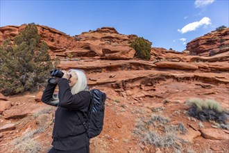 Senior woman uses binoculars while hiking in Grand Staircase-Escalante National Monument