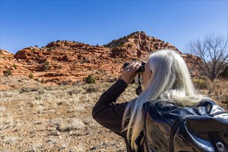 Woman using binoculars while hiking in Grand Staircase-Escalante National Monument
