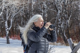 Senior woman using binoculars while hiking