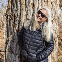 Portrait of senior woman standing in front of cottonwood tree