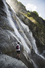 Man standing near Sofiyskiye Vodopady waterfall in Caucasus Mountains