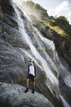 Man standing near Sofiyskiye Vodopady waterfall in Caucasus Mountains