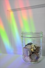 Jar of coins with rainbow light