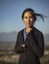 Portrait of pensive woman in sports clothing standing in landscape