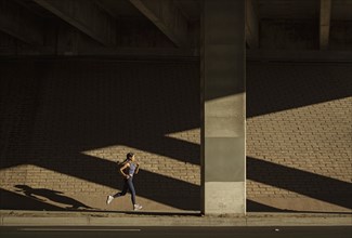 Woman jogging near brick wall in sunlight