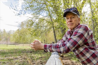 Portrait of senior farmer leaning on wooden fence near Sun Valley