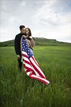 Young couple with American flag in wheat field