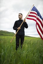 Young man with American flag in wheat field