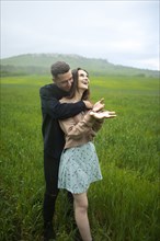Young couple embracing in wheat field in rain