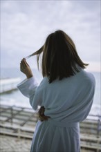 Rear view of woman in bathrobe in hotel with view on sea