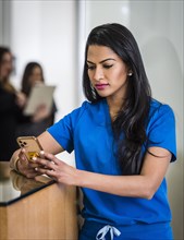 Female doctor with smart phone at reception desk
