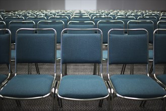 Rows of empty blue chairs in conference room